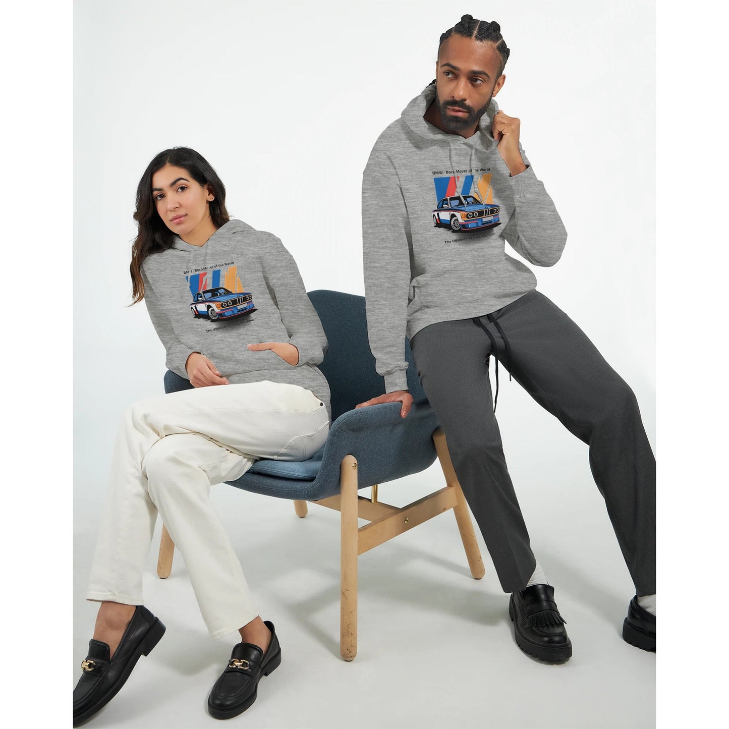 two models wearing grey born to race unisex hoodies with car graphic, one sitting on chair and one standing.