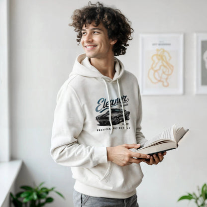 Young man wearing white Eleanor Hoodie with muscle car print, holding a book indoors