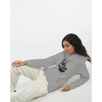 Woman wearing a grey Born to Race Unisex Hoodie with a colorful car graphic, paired with white pants, lying down against a plain white background.