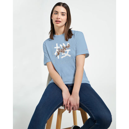 Frau trägt hellblaues Crewneck T-Shirt mit Kirschblüten Träume Design, kombiniert mit Jeans, auf weißem Hintergrund.