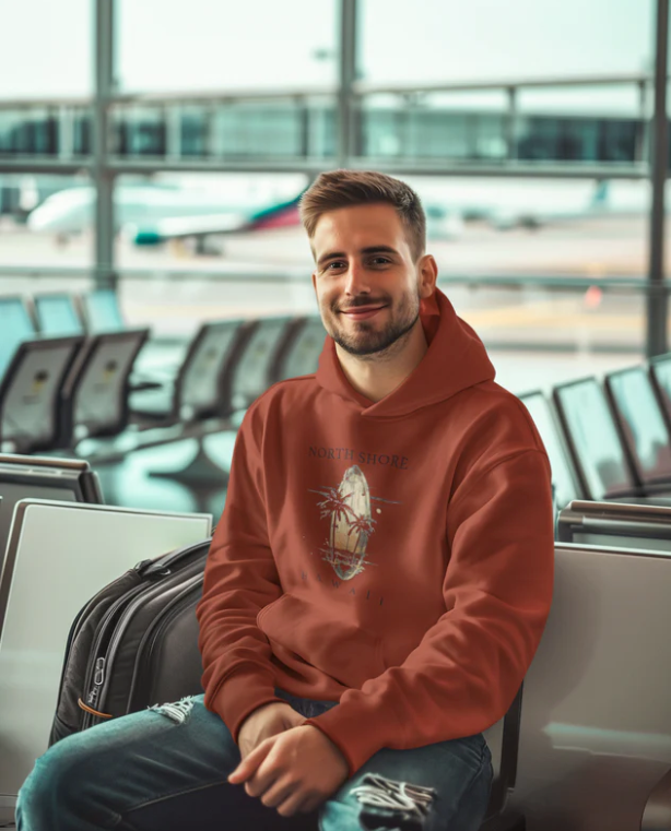 junger mann trägt pullover hoodie sommer feeling hawaii aus weichem baumwoll-polyester-mix am flughafen.