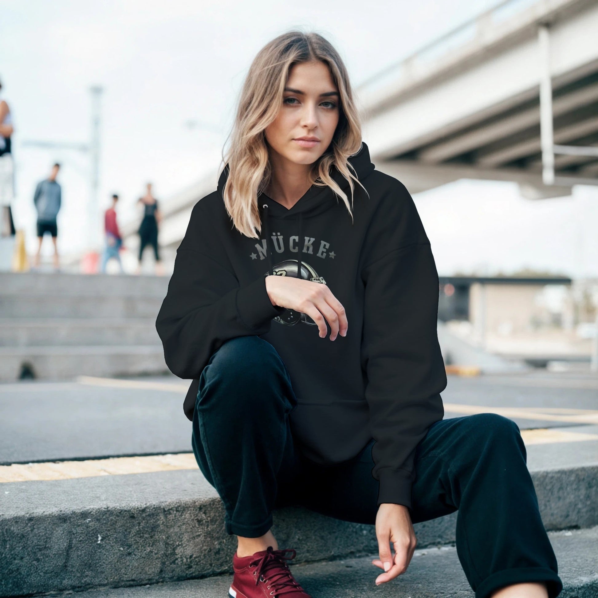 Frau trägt schwarzen Bud Spencer Hoodie mit Kapuze und Kängurutasche, moderner Freizeitlook, Outdoor urban