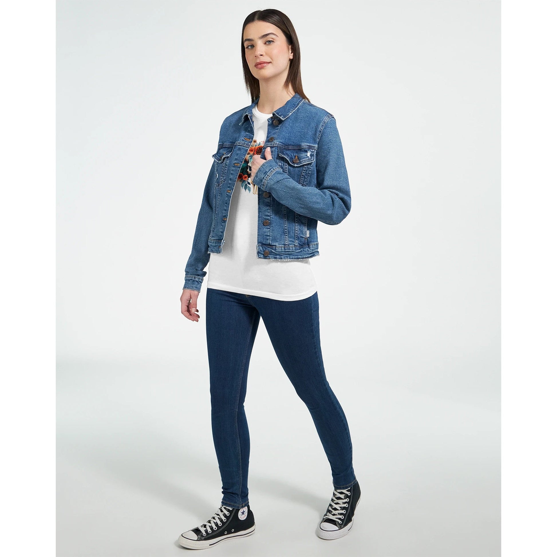 Frau trägt Premium Texas Flower T-Shirt mit Blumenmotiv, Jeansjacke und Sneakern in lässigem Stil