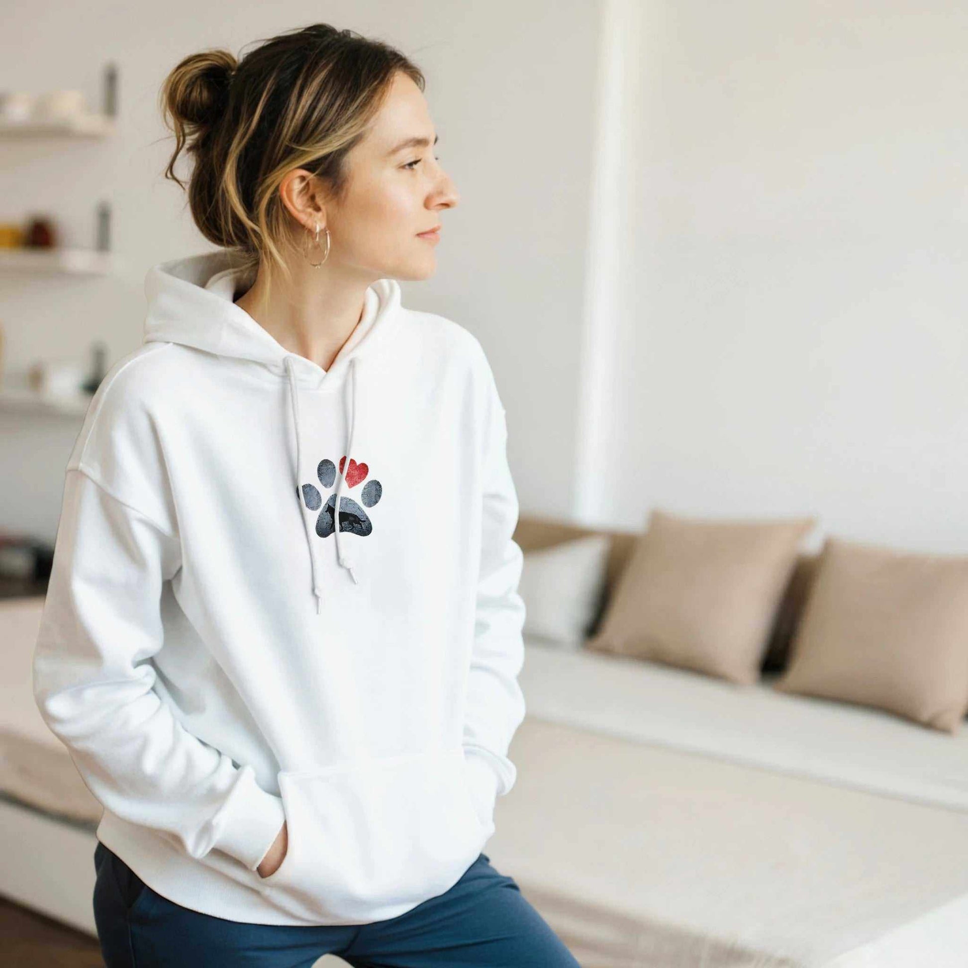 Frau trägt weißen Shepherd-Liebhaber Hoodie mit Pfoten- und Herzmotiv, gemütlich und stilvoll zu Hause