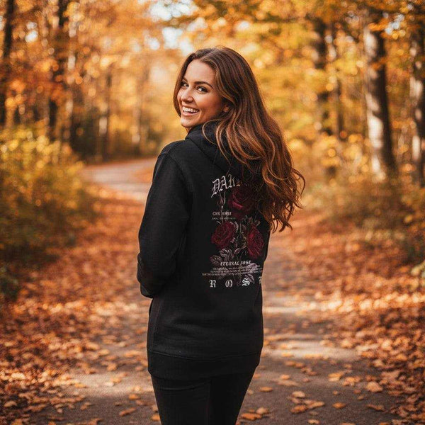 Frau trägt schwarzen Rosenblüte Hoodie mit Rosenmotiv im herbstlichen Waldweg