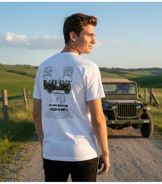 Junger Mann trägt weißes Vintage Jeep Abenteuer Shirt vor grünem Offroad-Gelände mit altem Jeep Fahrzeug im Hintergrund